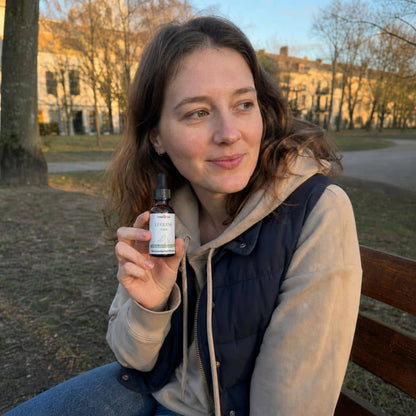 Frau, die eine Flasche Luzerner CBD Öl im Freien in einem Park hält