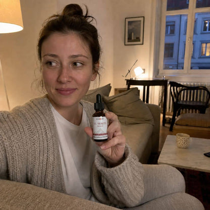 Frau, die eine Flasche St. Moritz CBD Öl im Wohnzimmer